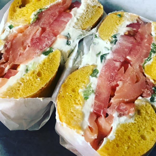 Two BGL bagels, sliced open, filled with cream cheese, smoked salmon, and herbs.