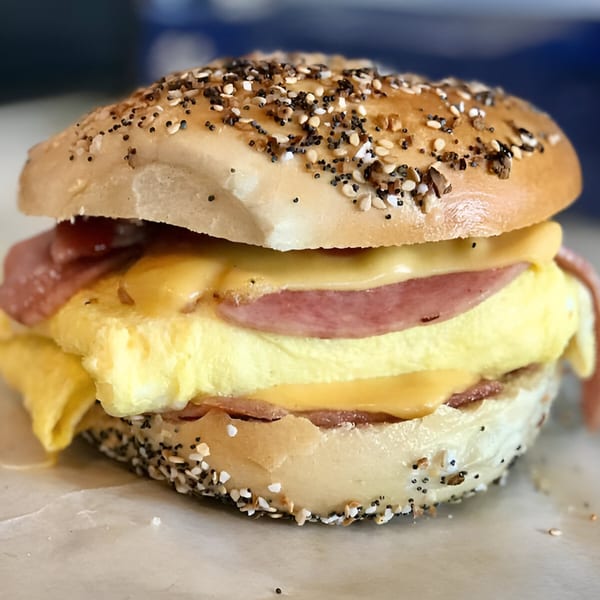 Close-up of a BGL everything bagel sandwich with egg, cheese, and meat.